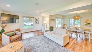 A spacious living room with a white sofa, a coffee table, and a dining area with a table and chairs. - Home on Legacy Hills Golf Course w/ Patio! (LaPorte)