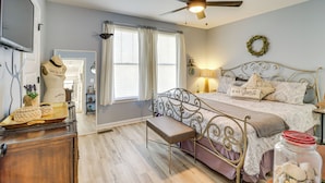 A bedroom with a bed, a ceiling fan, a bench, a dresser, and a window with curtains. - Fall Fun Near Potomac River & Colonial Beach (Colonial Beach)