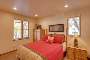 A bedroom with a large bed, a nightstand, a dresser, and two windows. - Patio & Mountain Views: Central Ouray Getaway! (Ouray)