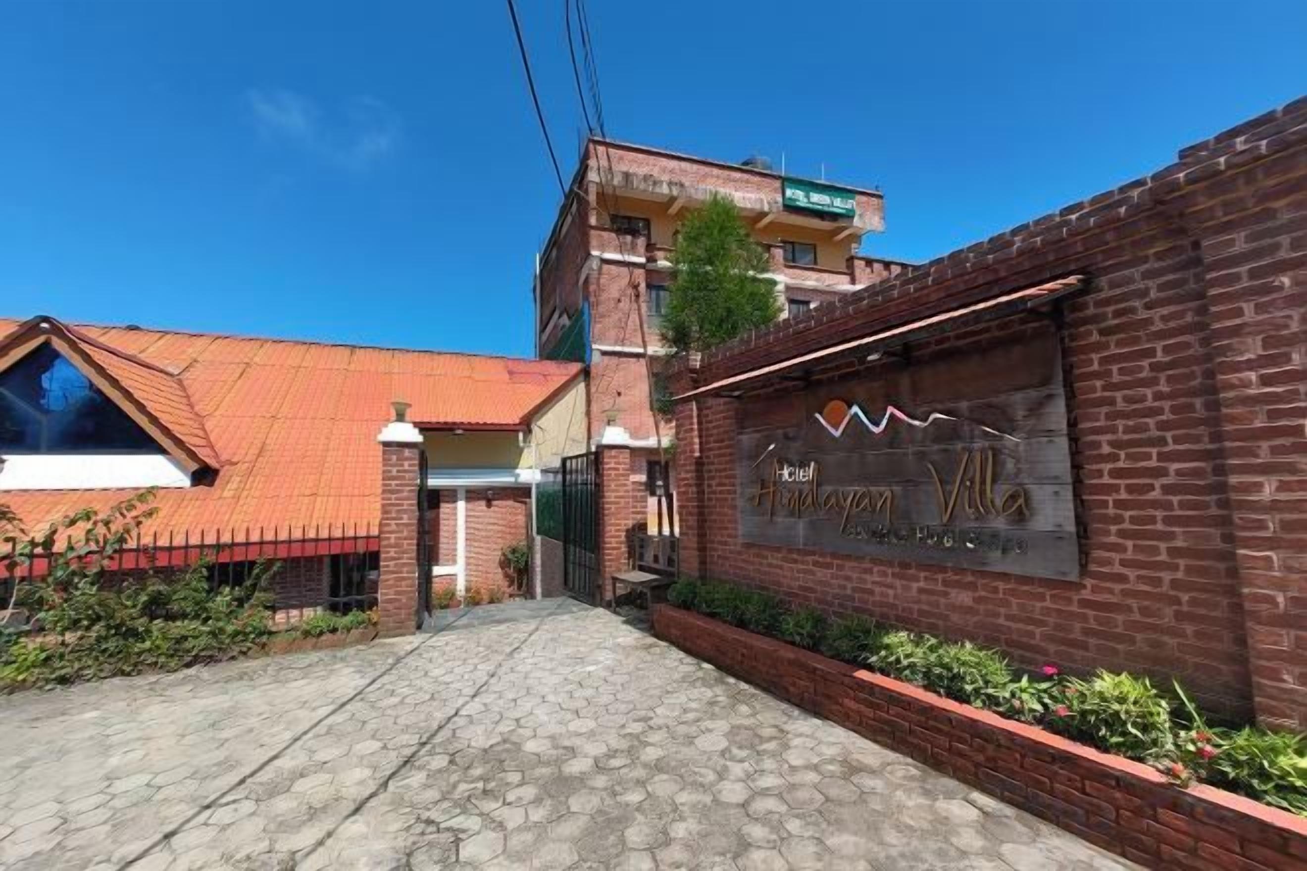 Entrada de hotel con fachada de ladrillo, una reja metálica y cielo despejado.