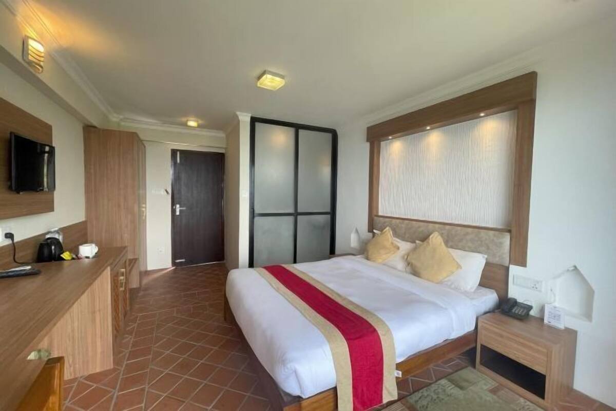A hotel room with a bed, bedside table, TV, and a wardrobe.