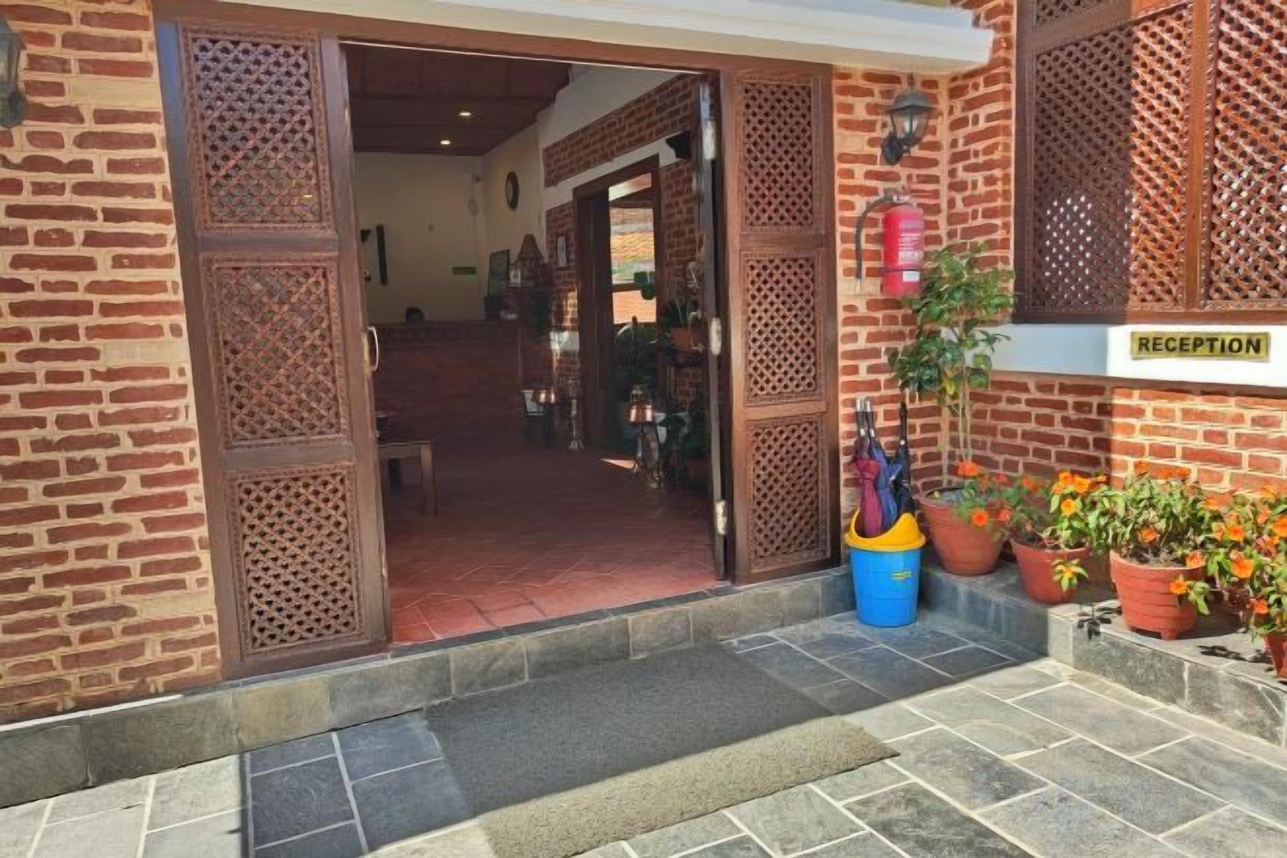 Un área de recepción con pared de ladrillo, puerta de madera y un letrero que dice 'RECEPTION'.