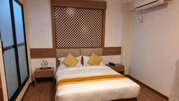 A hotel room with a bed, bedside tables, a decorative headboard, and a window.