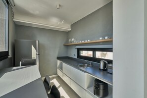 A compact kitchen with a refrigerator, sink, and coffee maker. - Alma Rentals French Palermo (Buenos Aires)