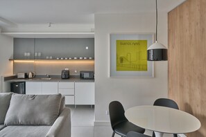 A modern kitchen with a dining area, a sofa, and a table with chairs. - Alma Rentals French Palermo (Buenos Aires)