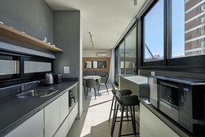 A modern kitchen with a built-in oven, a coffee machine, and a dining area with a table and chairs. - Alma Rentals French Palermo (Buenos Aires)