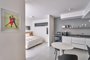 A modern hotel room with a bed, a dining table, and a kitchenette. - Alma Rentals French Palermo (Buenos Aires)