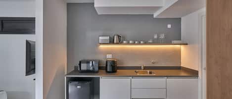 Uma cozinha moderna com micro-ondas embutido, cafeteira e um pequeno cesto de lixo.