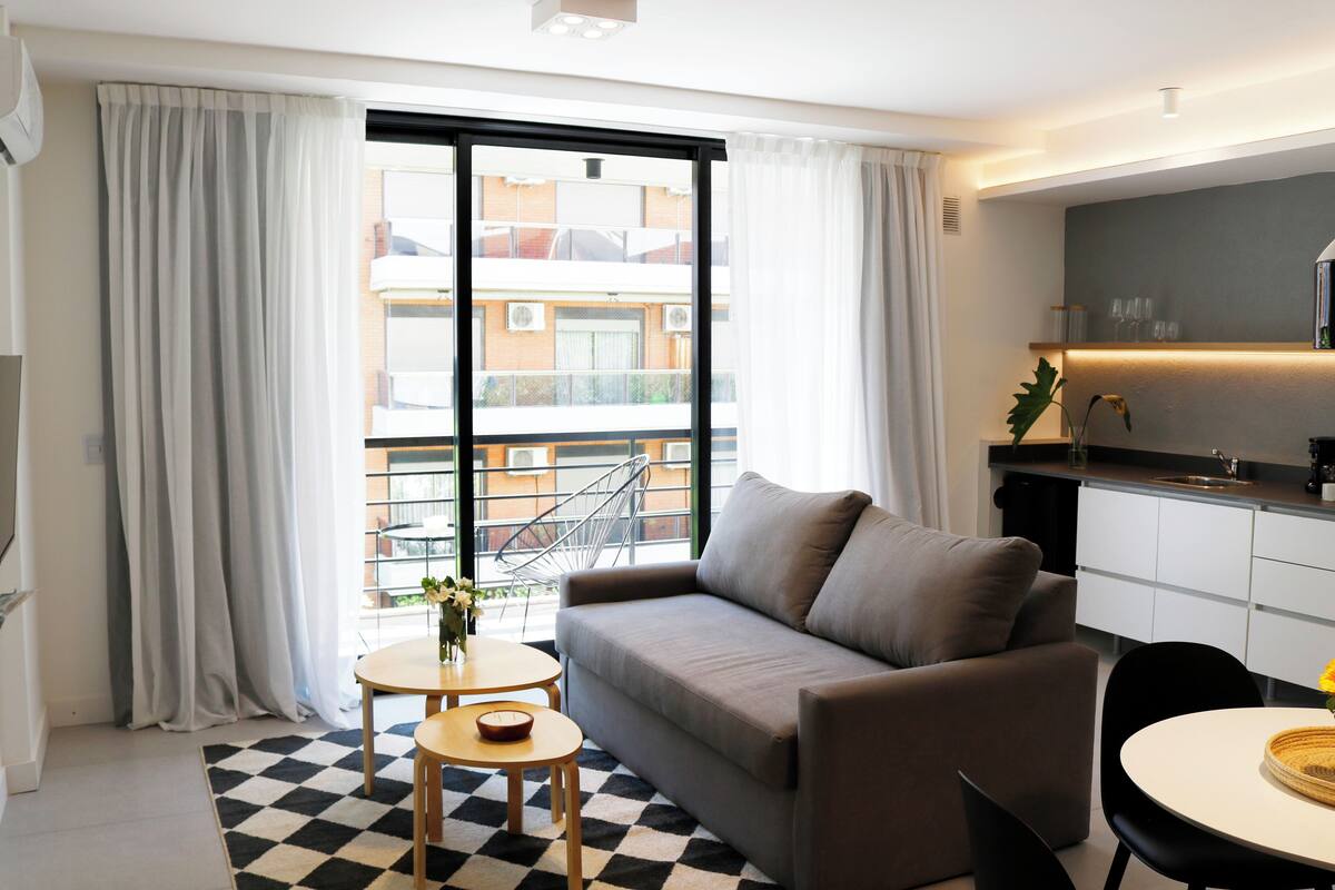 A modern living room with a sofa, a small round table, and a checkered floor.