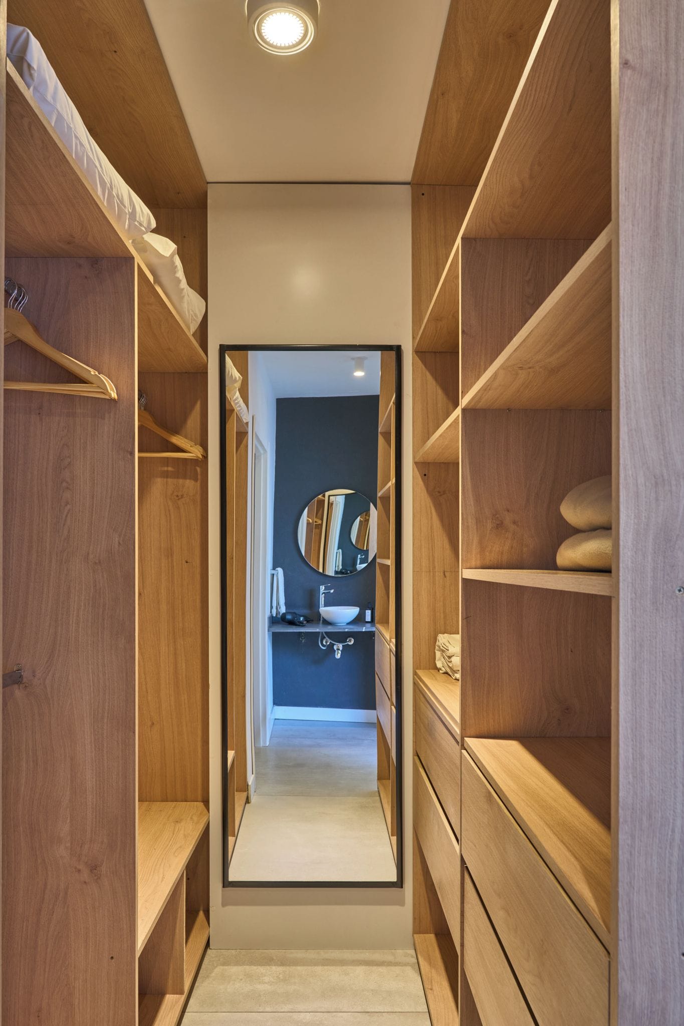 A walk-in closet with wooden shelving and a mirrored closet door.