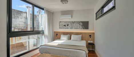 Une chambre à coucher moderne avec une grande fenêtre, un lit, un banc et une œuvre d’art représentant une carte accrochée au mur.