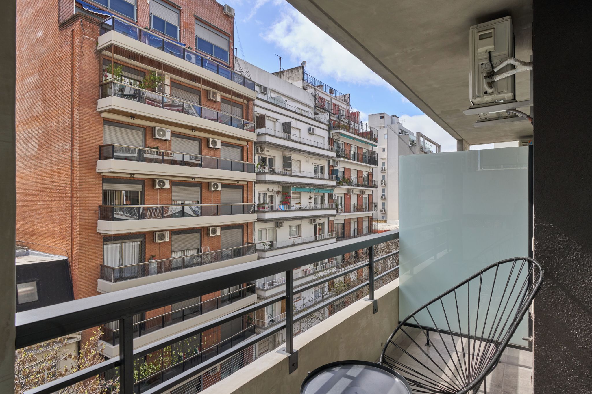 A multi-story residential building with balconies, a concrete structure, and a clear sky.