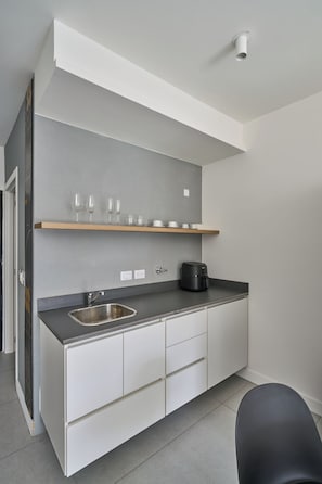 A modern kitchen with a built-in sink, a coffee machine, and a shelf with glasses. - Alma Rentals French Palermo (Buenos Aires)