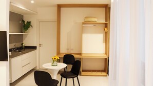 A compact kitchen with a sink, a small dining table, and chairs. There is a wooden shelf above the counter with a towel and a plant. - Alma Rentals French Palermo (Buenos Aires)