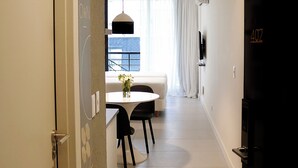 A modern hotel room with a dining area, a sofa, and a TV mounted on the wall. - Alma Rentals French Palermo (Buenos Aires)