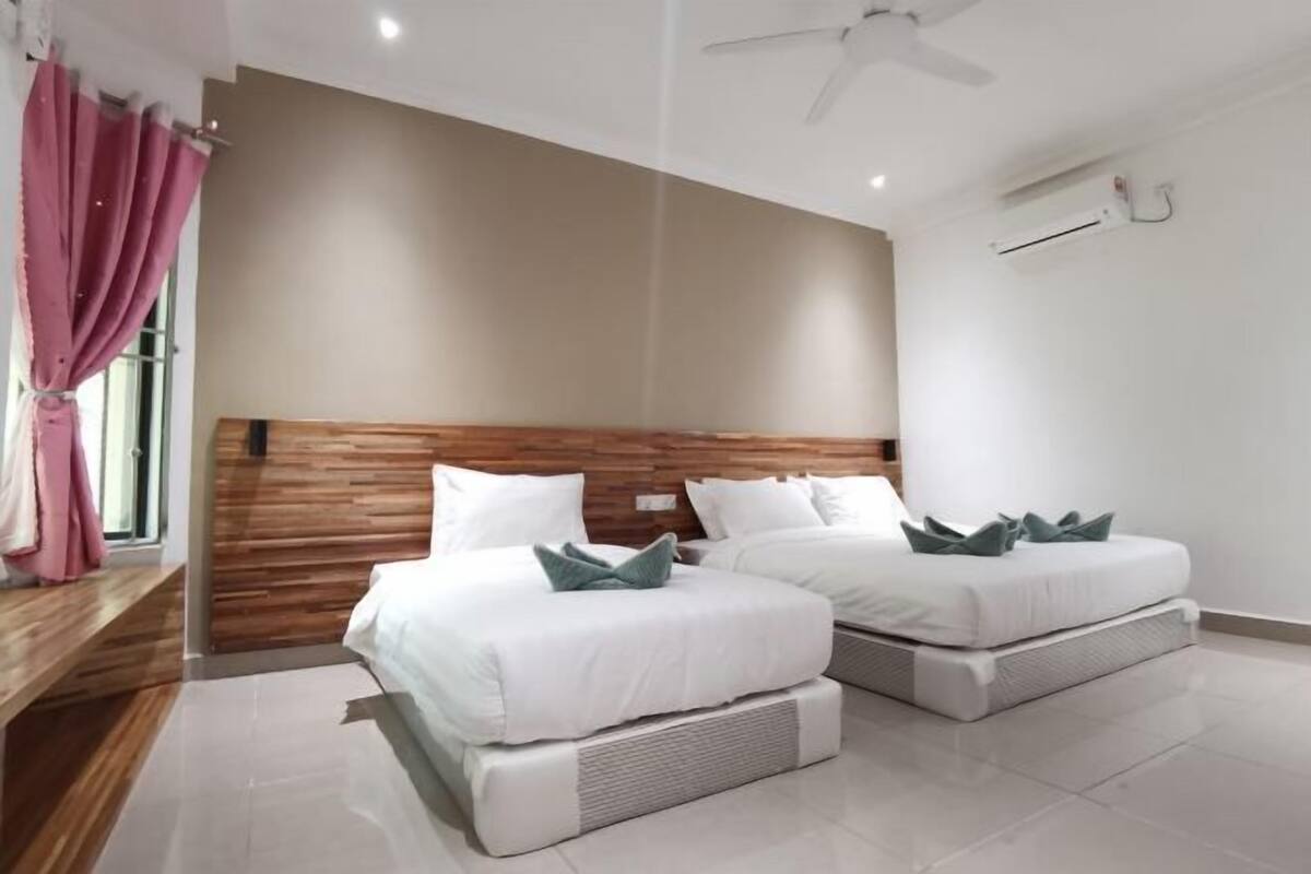 A modern hotel room with two beds, a wooden headboard, white bedding, and a ceiling fan.
