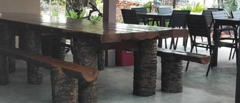 A dining area with a long wooden table supported by cylindrical concrete pillars, surrounded by chairs.