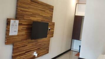 A reception area with a wooden wall panel, a mounted flat-screen TV, and a whiteboard with a notice.