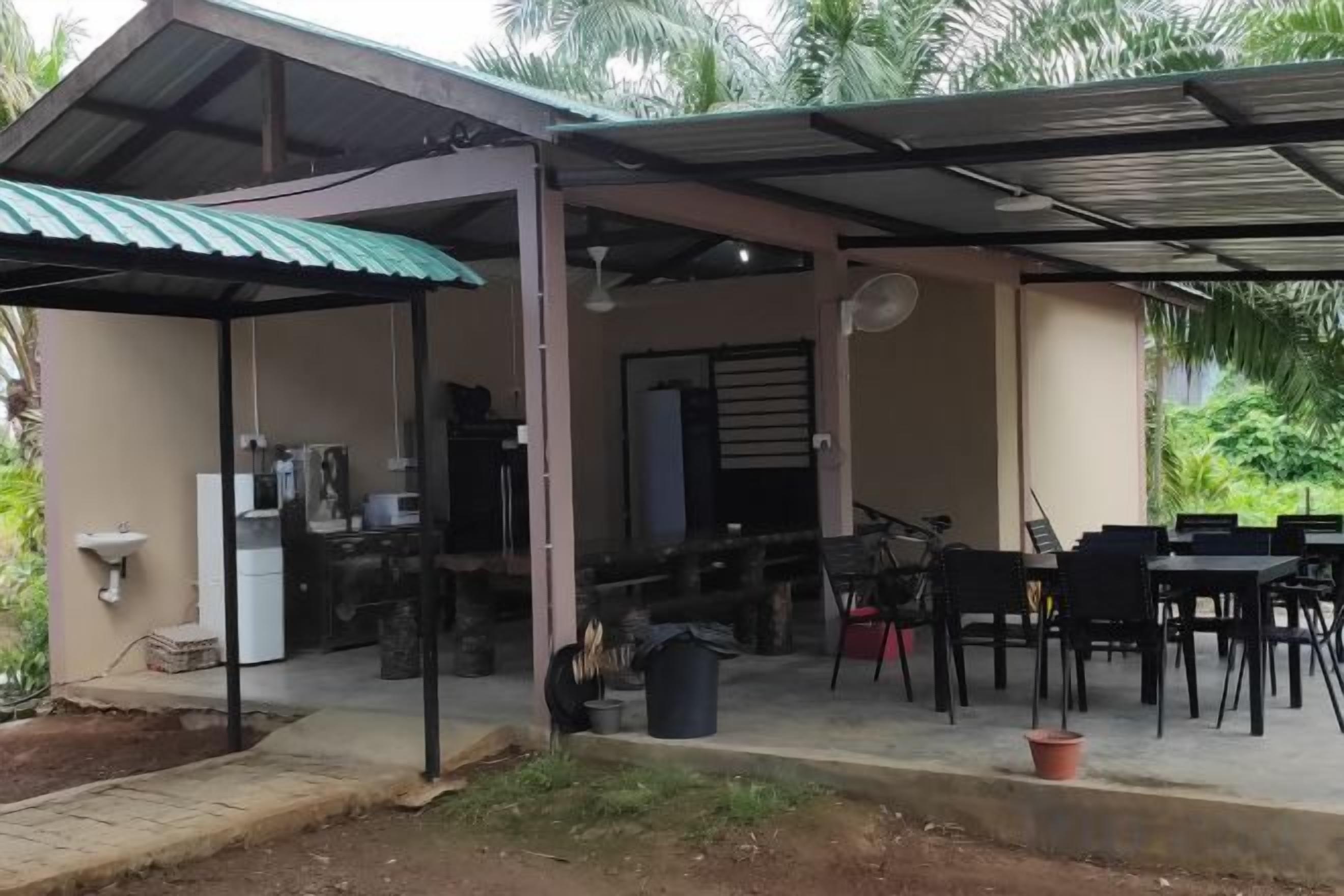 A covered outdoor area with a dining table and chairs, a sink, and a refrigerator.