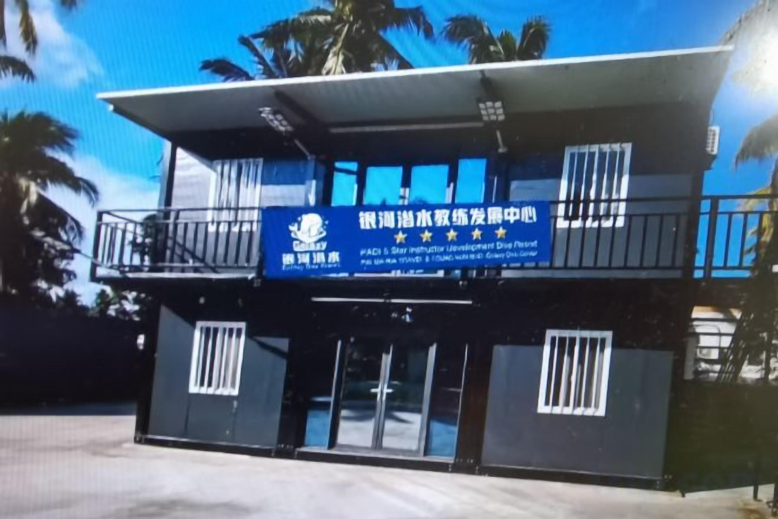 A two-story building with a blue signboard and a balcony.
