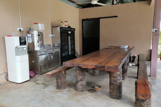 A dining area with a wooden table and chairs, a refrigerator, a sink, and a door.