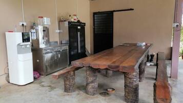 A dining area with a wooden table and chairs, a refrigerator, a sink, and a door.