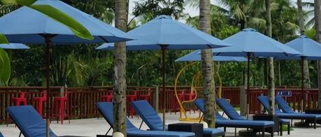 A poolside area with lounge chairs and umbrellas.