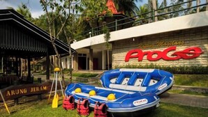 Ein blaues Schlauchboot mit Rettungswesten und Paddeln, ein Schild mit der Aufschrift "ARUNG JERAM" sowie ein Gebäude mit den Schildern "Rafting Magelang" und "ProGo".