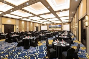 A conference room with multiple tables and chairs, a large screen, and a carpeted floor. - Puri Asri Hotel & Resort Magelang (Central Magelang)