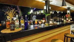 Eine Bar mit verschiedenen Spirituosenflaschen, einer Theke und Hockstühlen.