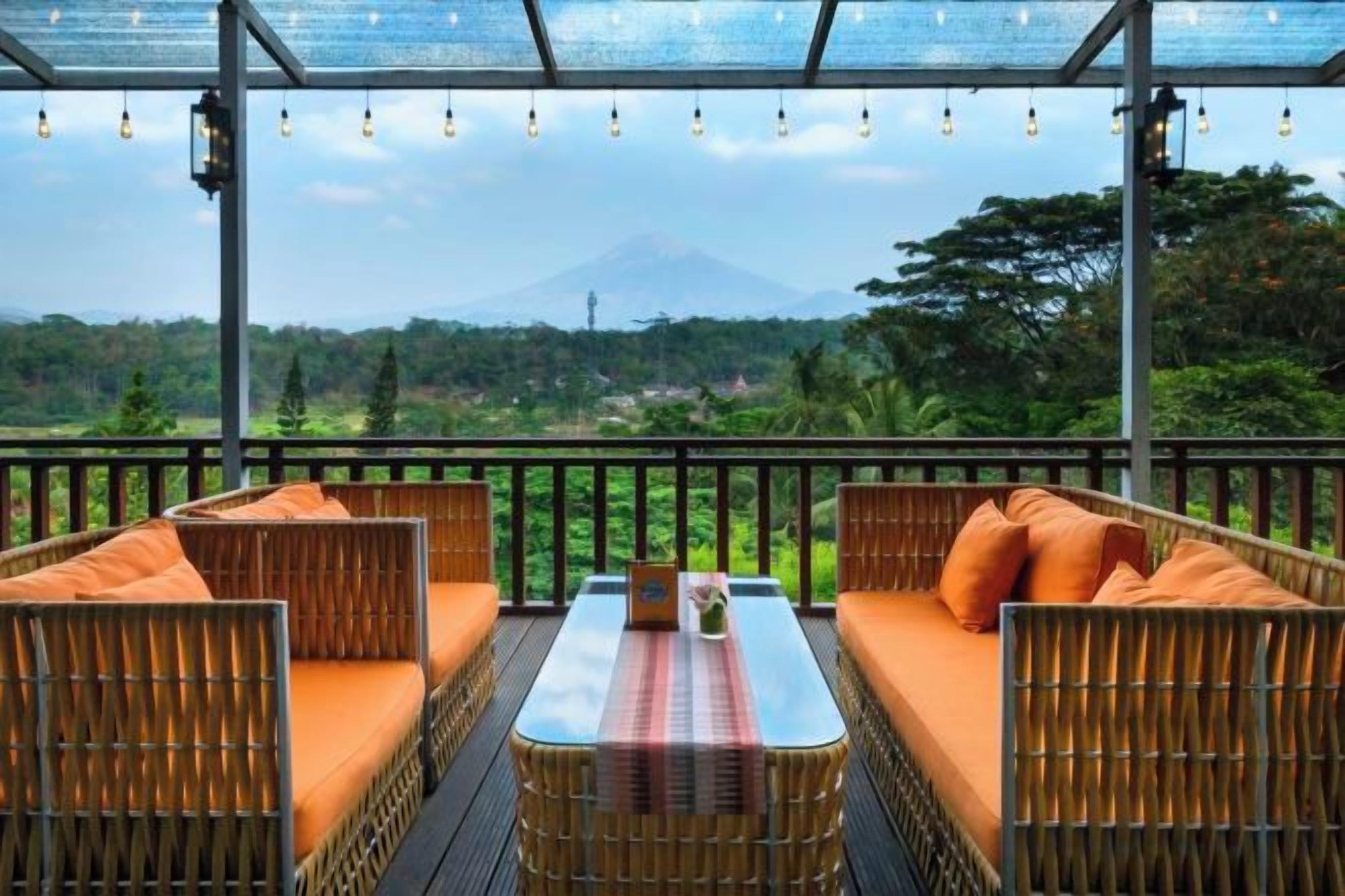 An outdoor seating area with wicker furniture and a table, overlooking a mountainous landscape.