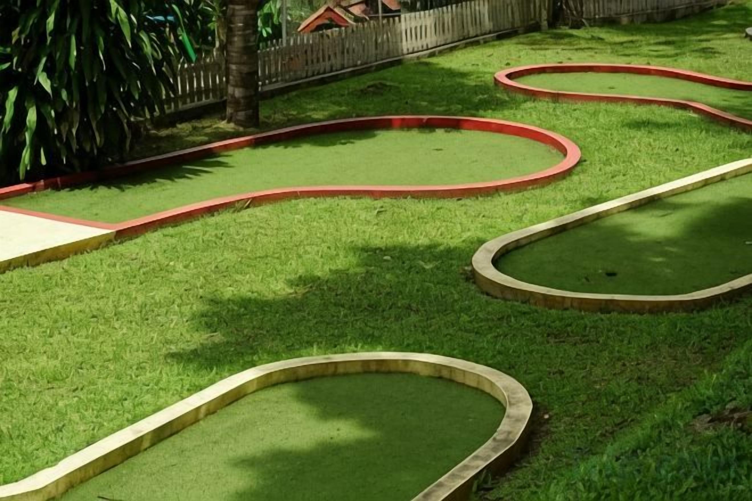 Um campo de minigolfe com grama verde e bordas vermelhas.