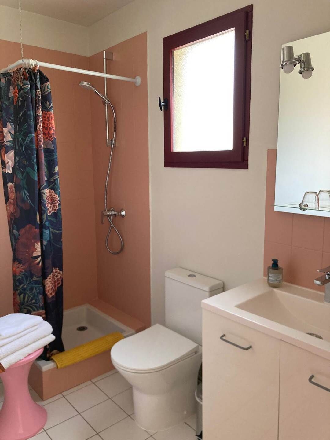 Une salle de bain avec une douche, des toilettes, un lavabo et une fenêtre.