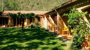 Un patio con techo de tejas, mobiliario exterior y montañas al fondo.