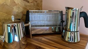 Een keuken met een roestvrijstalen espressoapparaat, een koffiekan en een metalen rek.