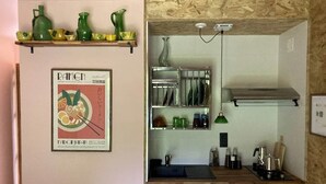 Een keuken met een houten plafond, een hanglamp, een ingelijst poster en planken met keukengerei.
