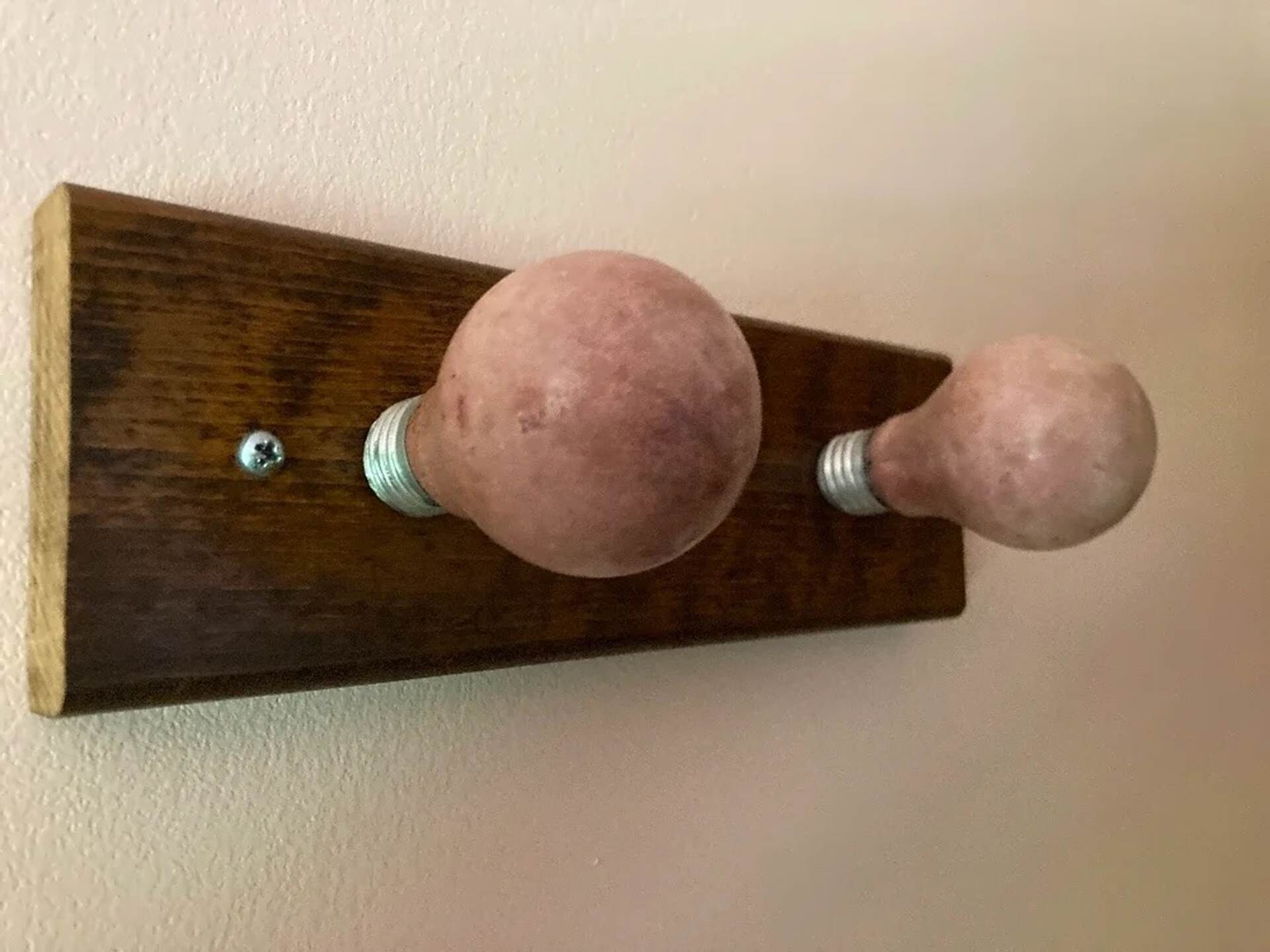 Il s’agit d’un objet en bois, fixé au mur, doté de deux boutons sphériques, et qui ressemble probablement à un porte-manteau ou à un accessoire similaire.