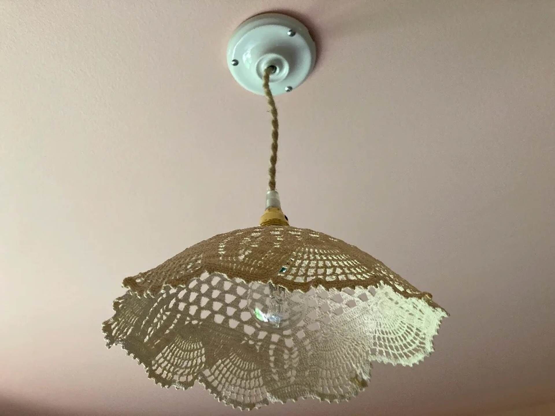 Un soffitto con una singola lampada a sospensione dotata di paralume all'uncinetto.