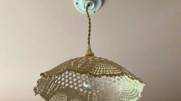 Un soffitto con una singola lampada a sospensione dotata di paralume all'uncinetto.