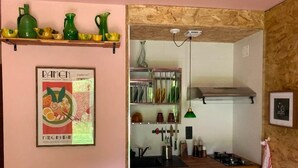 Een kleine keuken met een houten plafond, een kleine koelkast en een plank met keukengerei.