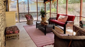 A cozy room with a red sofa, wicker furniture, and a large window offering a view of the outdoors. - Cozy & Spacious 2Bed, 2Bath in the heart of Winfield (Winfield)