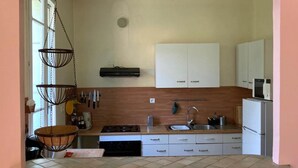 A compact kitchen with a stove, sink, and white cabinets. There is a hanging light fixture and a microwave on the countertop. - Studio (2 people) (SAHORRE)