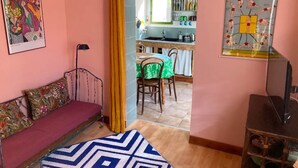 A cozy room with a sofa, a patterned rug, a dining area with a table and chairs, and a kitchen visible through an open doorway. - Studio (3 people) (SAHORRE)
