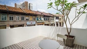 En tagterrasse med fliset gulv, et lille rundt bord og en potteplante.