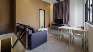 A modern living room with a sofa, a dining table, and a TV. - Hutton Central Hotel Managed By The Ascott Limited  (George Town)