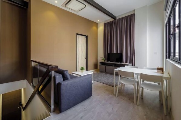 A modern living room with a sofa, a dining table, and a TV. - Hutton Central Hotel Managed By The Ascott Limited  (George Town)