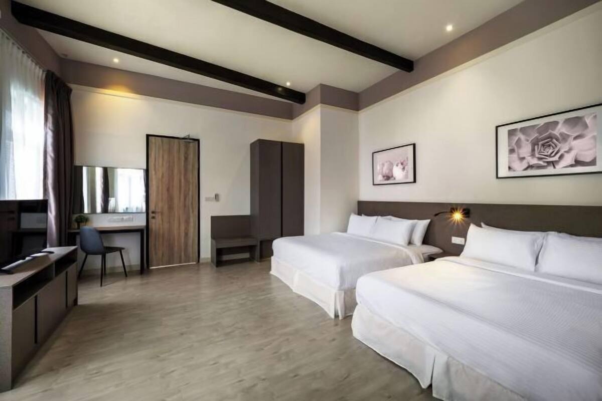A hotel room with two beds, a desk, a chair, and artwork on the walls.