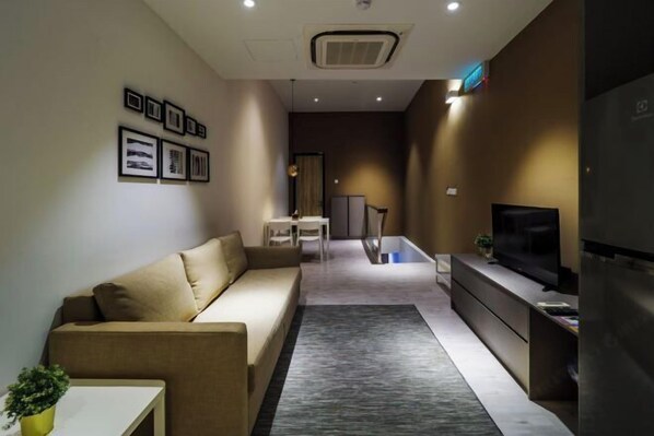 A modern living room with a sofa, a flat-screen TV, a dining area, and framed pictures on the wall. - Hutton Central Hotel Managed By The Ascott Limited  (George Town)