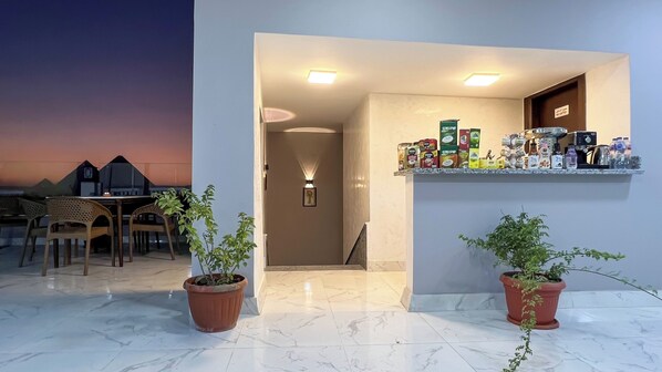 A modern hotel lobby with a marble floor, potted plants, a reception desk, and a display of bottled beverages. - asser hotel pyramids (Giza)