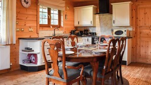 A wooden cabin interior with a dining table set for four, surrounded by wooden chairs.